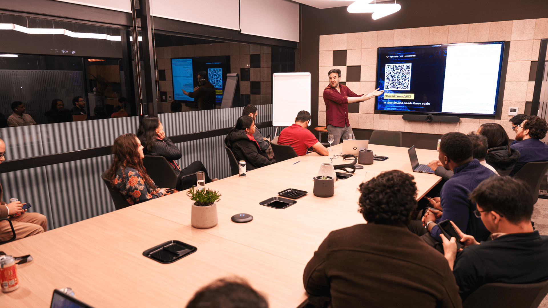 A group of people sit in a boardroom focusing  on a man delivering a presentation