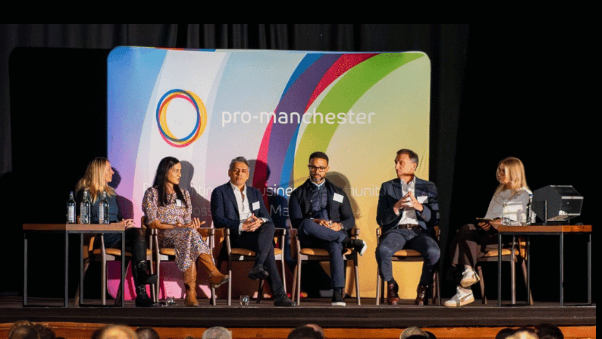 A panel discussion on stage with pro-manchester branding behind