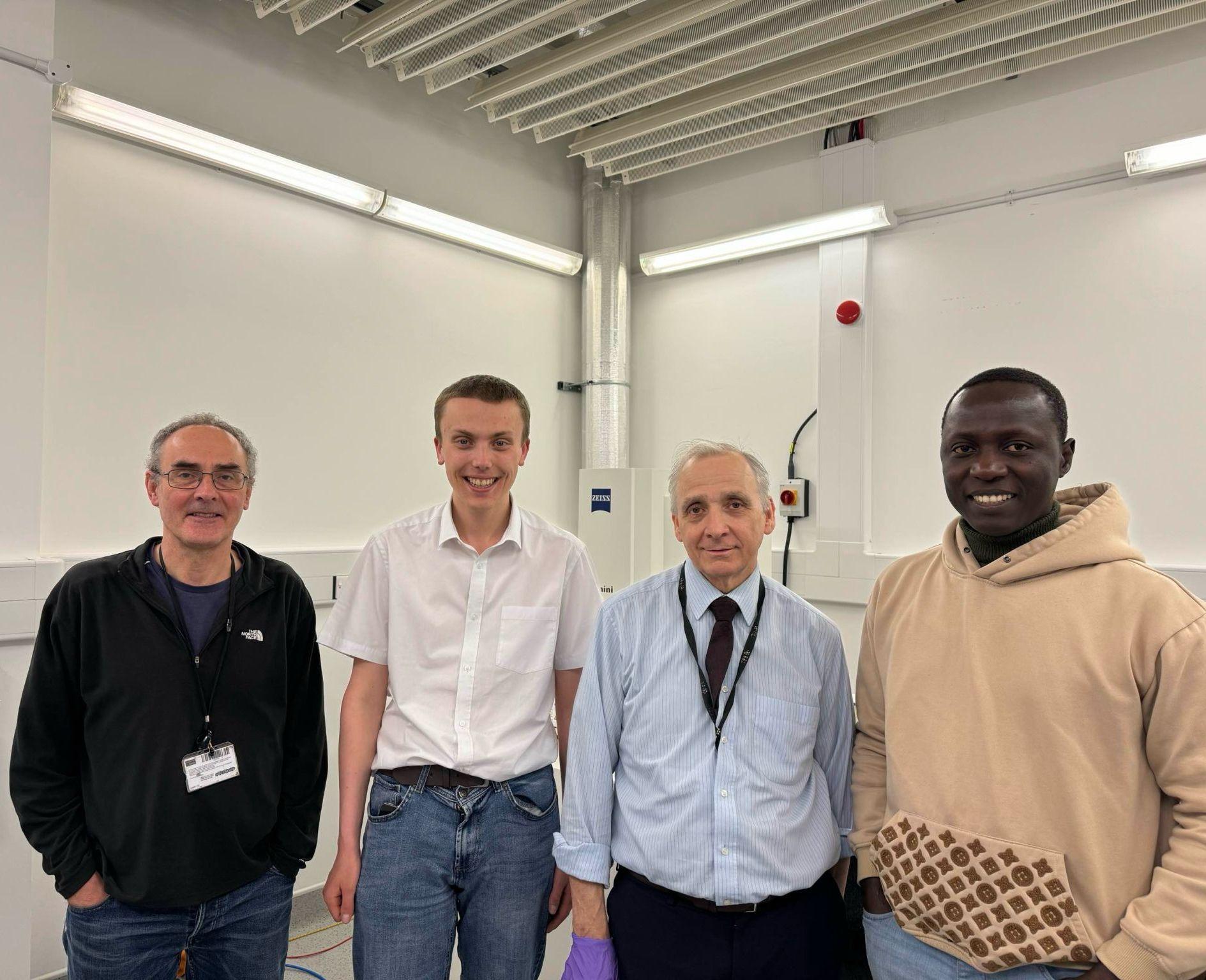 Aqua Catalysis (four men) smiling at camera while standing in workspace