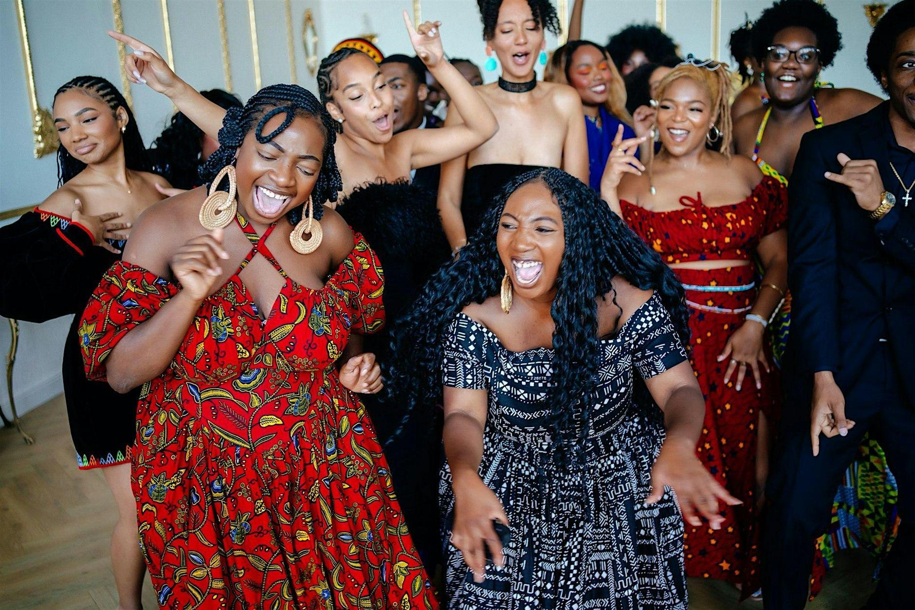A party of beautifully dressed black creative women dance and sign together in a candid, expressive image.